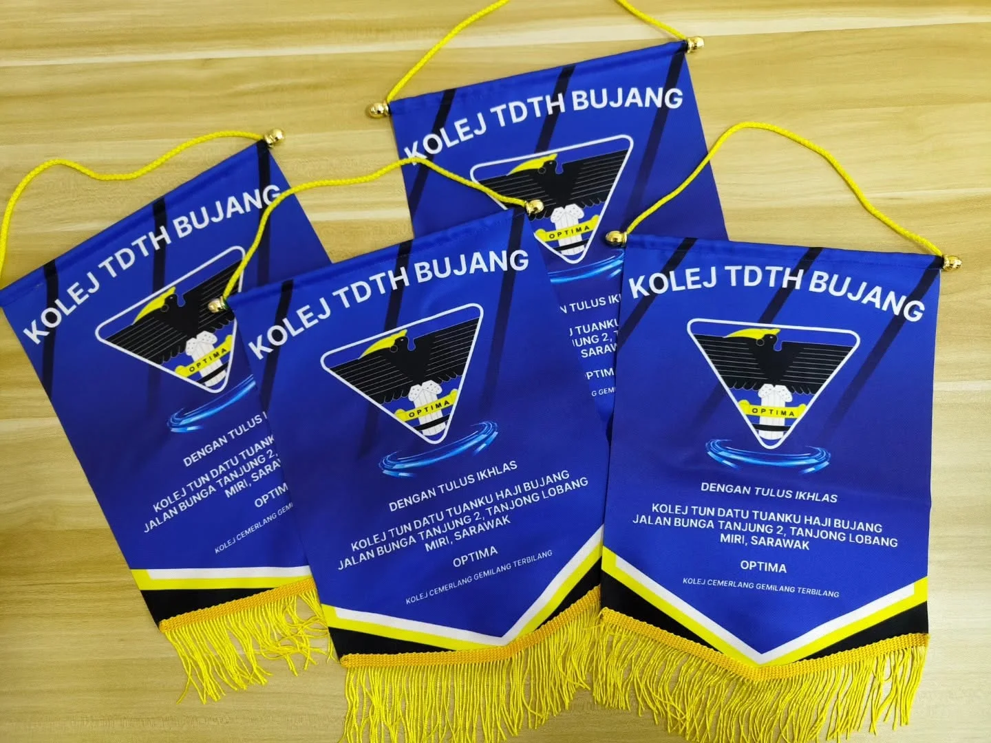 Blue custom college pennants with yellow hanging cords and fringe