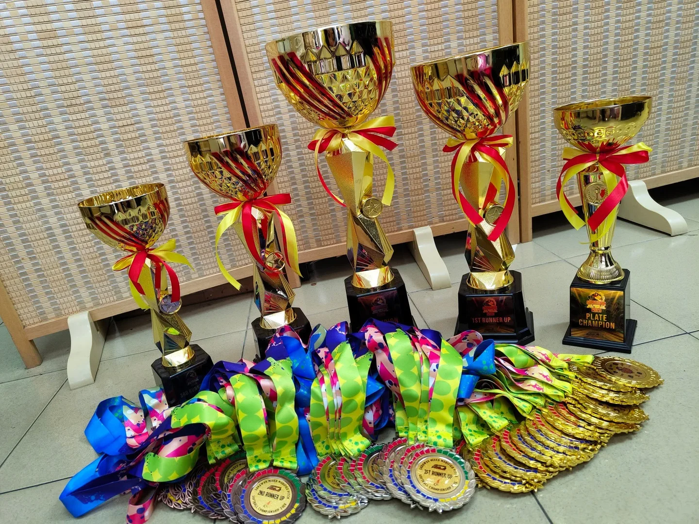 Gold trophies and event medals with colourful printed ribbons